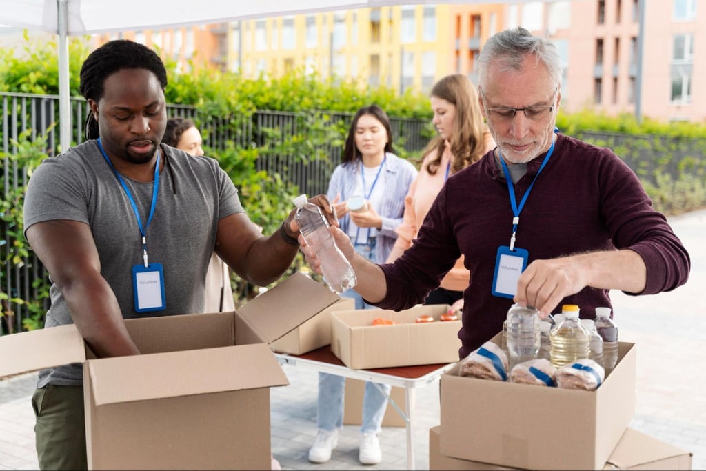 Diverse group of volunteers packing food and water into cardboard boxes at a community donation drive