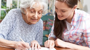Volunteer assisting elderly woman with a book