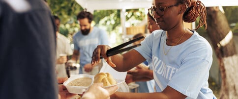 Woman volunteering with a nonprofit to serve food to beneficiaries.