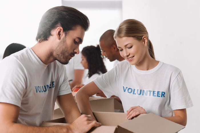 Two volunteers smile while packing boxes